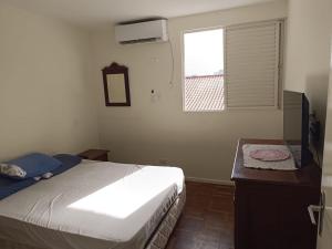a bedroom with a bed and a desk and a window at Sobrado charmoso 2 in Guaratuba