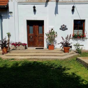 a white house with a wooden door and potted plants at Dworek Marmis - idealny dla rodzin in Mirsk