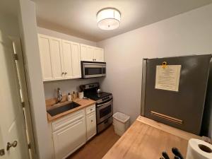 a kitchen with white cabinets and a black refrigerator at Telluride Creekside Condo 3 Min to Chair 7 in Telluride