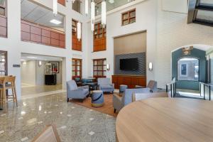 a lobby with chairs and a table and a tv at Drury Inn & Suites Joplin in Joplin