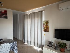 a living room with white curtains and a television at Apt in Playa den Bossa next Ushuaia, beachfront, reliable host in Ibiza Town