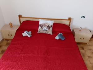 a bed with a red comforter with a dog pillow on it at Foresteria del Passo Forcora in Maccagno Superiore +15 photos