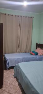 a bedroom with two beds and a curtain at Pousada Bela Vista Santo Antônio do Manhuaçu in Caratinga
