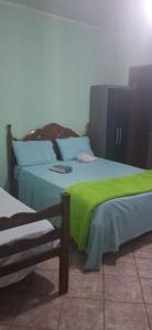 two beds with green sheets in a room at Pousada Bela Vista Santo Antônio do Manhuaçu in Caratinga