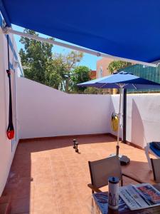a patio with a blue umbrella and a table and chair at Playa de Mogán in Playa del Cura