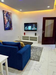 a living room with a blue couch and a tv at Résidence SG2 in Thiès