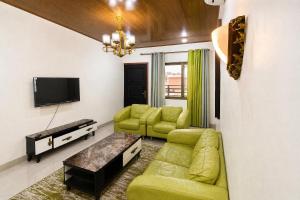 a living room with a green couch and a tv at Raoul Immobilier JDMK in Brazzaville