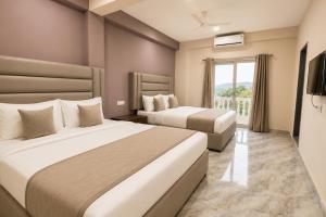 a hotel room with two beds and a window at Home Stay CampoDeVista in Calangute