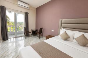 a bedroom with a bed and a window with a table at Home Stay CampoDeVista in Calangute