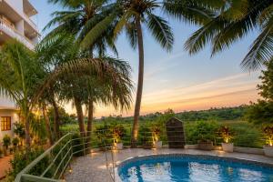 a resort pool with palm trees and a sunset at Home Stay CampoDeVista in Calangute +9 photos