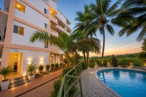 a hotel with a swimming pool and palm trees at Home Stay CampoDeVista in Calangute