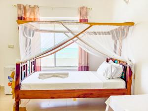 a bedroom with a canopy bed with a window at Visitors Inn Zanzibar in Jambiani