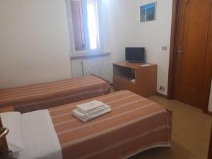 ein Hotelzimmer mit zwei Betten und einem Fernseher in der Unterkunft La Colombella in Montemonaco