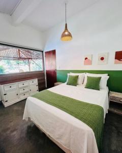 a bedroom with a large bed with green and white sheets at Refugá in Porto Seguro