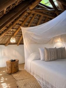 a bedroom with a white bed with a tree stumpemate sidx sidx sidx at Casa Coconut in Puerto Escondido