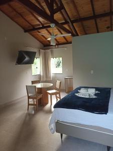 a bedroom with a bed and a table and chairs at Chalé caminho das cachoeiras in São Thomé das Letras