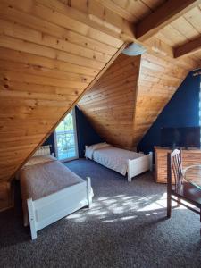 a attic bedroom with two beds and a wooden ceiling at Eleni Pokoje Gościnne in Bukowina Tatrzańska