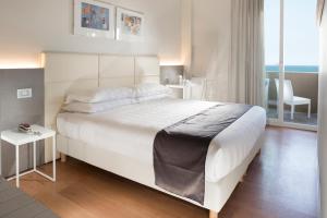 a bedroom with a large white bed and a chair at Hotel Ascot & Spa in Rimini