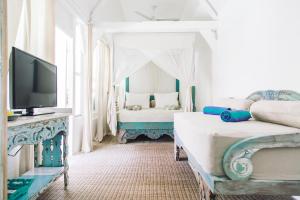 a bedroom with two beds and a tv in it at Palmeto Village in Gili Trawangan