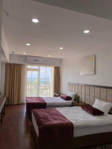 a hotel room with three beds and a window at Gold ASSN in Cholpon-Ata