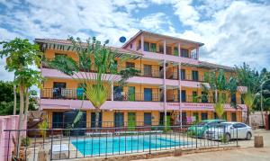 a pink building with a pool in front of it at Tranquil Terrace Cottages Diani in Diani Beach