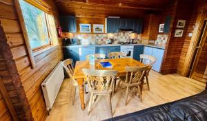 a kitchen with a wooden table and chairs in a cabin at Tor View Lodge with Hot Tub & Sauna - Spa Resort - South Devon in Chudleigh