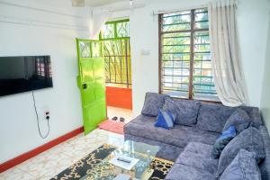 a living room with a couch and a tv at Tranquil Terrace Cottages Diani in Diani Beach