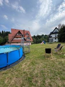 a pool with a slide and a chair in a yard at Eleni Pokoje Gościnne in Bukowina Tatrzańska