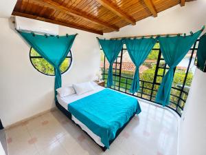 a bedroom with a bed with blue sheets and windows at El Bosque in Nocaima