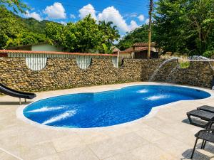 a swimming pool next to a stone wall with a fountain at El Bosque in Nocaima