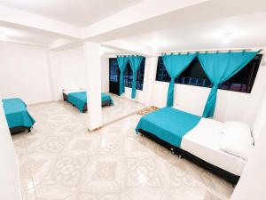 two beds in a room with blue curtains at El Bosque in Nocaima