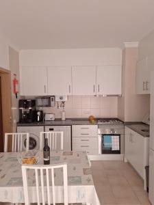 a kitchen with white cabinets and a table with chairs at Cristais do Mar in Armação de Pêra