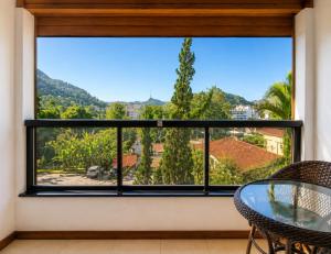 ein Zimmer mit großem Fenster, Tisch und Stühlen in der Unterkunft Hotel Willisau in Teresópolis