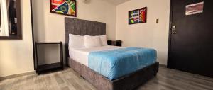 a bedroom with a bed with a blue blanket on it at Hotel el Duque Internacional, Bogotá in Bogotá