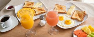 a table with breakfast foods and two glasses of juice at Hotel el Duque Internacional, Bogotá in Bogotá