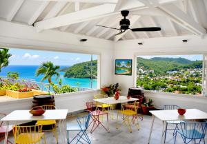 a restaurant with tables and chairs and a view of the ocean at Le Panoramic in Les Trois-Îlets