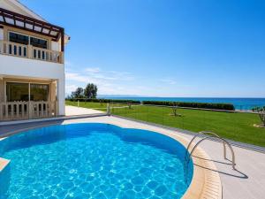 a swimming pool in front of a house with the ocean at Villa Bella Ena in Nea Dimmata