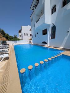 a swimming pool with stools next to a building at Andalucia Family-Only Aparthotel in Cabo Negro