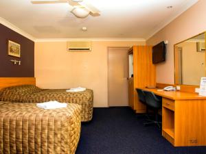a hotel room with two beds and a desk at SunPalms Motel in Rockhampton