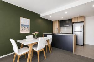 a kitchen and dining room with a white table and chairs at Lakeview on Grazier in Belconnen