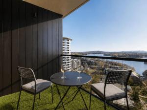 a table and two chairs on a balcony with a view at Lakeview on Grazier in Belconnen