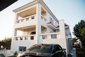 a white building with a car parked in front at Exclusive Villa with Pool in Káto Ássos