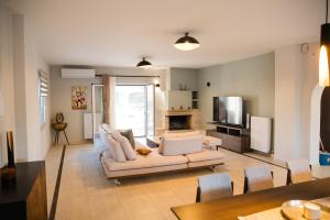 a living room with a white couch and a tv at Exclusive Villa with Pool in Káto Ássos
