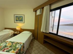 a hotel room with two beds and a large window at Ingleses Praia Hotel - Com Piscina Aquecida in Florianópolis +133 photos