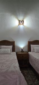 a bedroom with two beds and a light on the wall at Casa Vielma in Tapalpa
