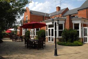 a patio with tables and chairs and an umbrella at Woodlands Hotel in Spalding