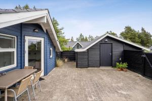 a backyard with a blue house and a table and chairs at 1395-Thisted-Revlingvej-5 in Nørre Vorupør