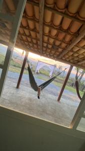 a person in a hammock hanging from a roof at Pousada flores de ipê in Capitólio
