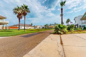 an empty street with palm trees and condos at Sunset Over Paradise in South Padre Island