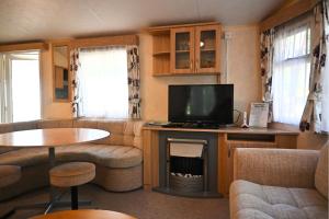 a living room with a tv and a couch and a table at Kota Kiva in Hulshorst
